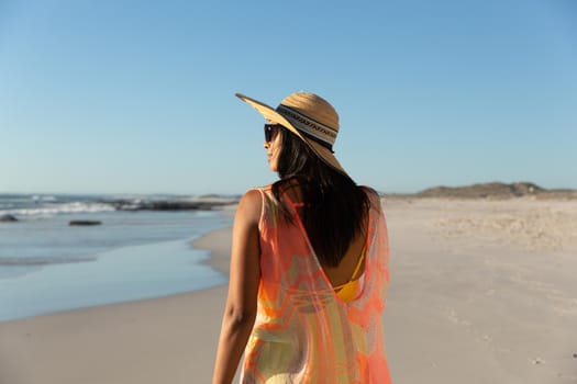 Happy mixed race woman on beach holiday looking away. healthy outdoor leisure time by the sea.