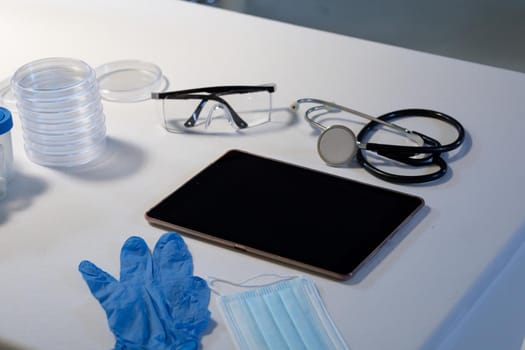 Desk in doctors surgery with tablet computer face mask gloves and stethoscope. telemedicine, healthcare and hygiene during covid 19 coronavirus pandemic.