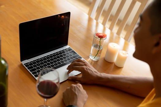Mixed race man sitting at table using laptop computer. staying at home in isolation during quarantine lockdown.