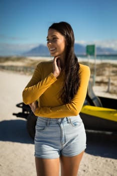 Portrait of happy caucasian woman staying next to beach buggy by the sea looking ahead smiling. beach break on summer holiday road trip.