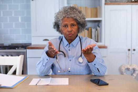 Portrait of african american senior female doctor talking looking at the camera at home. distant communication and telemedicine consultation concept.