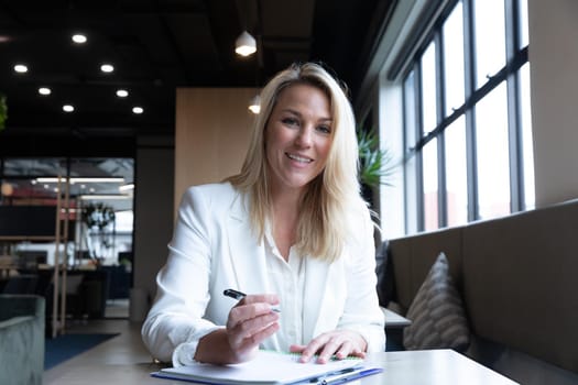 Caucasian businesswoman sitting having video chat going through paperwork in modern office. business modern office workplace technology.