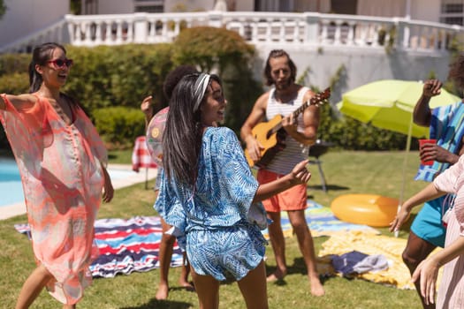 Diverse group of friends having fun and dancing at a pool party. Hanging out and relaxing outdoors in summer.