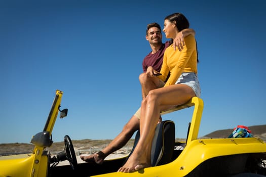 Happy caucasian couple sitting in beach buggy by the sea talking. beach break on summer holiday road trip.
