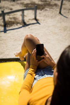 Midsection of caucasian woman lying on a beach buggy by the sea using smartphone. beach break on summer holiday road trip.
