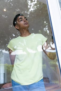 Mixed race man looking through a window and thinking. staying at home in isolation during quarantine lockdown.
