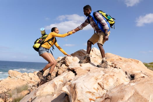 Fit afrcan american couple wearing backpacks hiking on the coast. healthy lifestyle, exercising in nature.