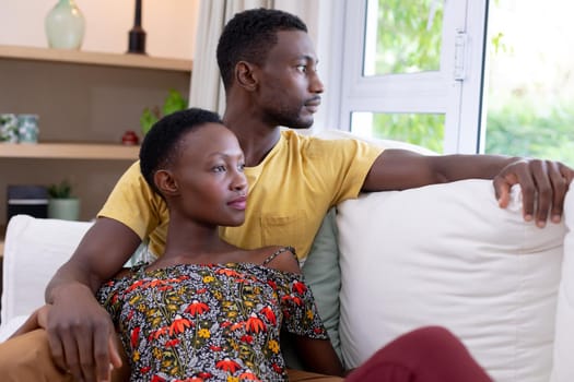 African american couple sitting on sofa embracing. staying at home in isolation during quarantine lockdown.