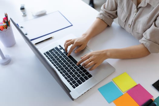 Asian businesswoman working in creative office. woman sitting at desk and using laptop computer. social distancing in workplace during covid 19 pandemic.