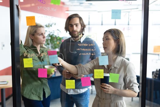 Diverse group of business people working in creative office. group of people brainstorming and taking notes on glass board. business people and work colleagues at a busy creative office.