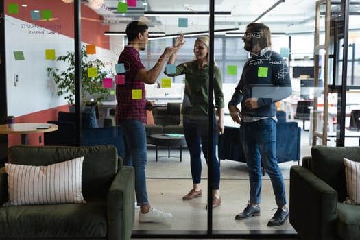 Diverse group of business people working in creative office. group of people brainstorming and taking notes on glass board. business people and work colleagues at a busy creative office.