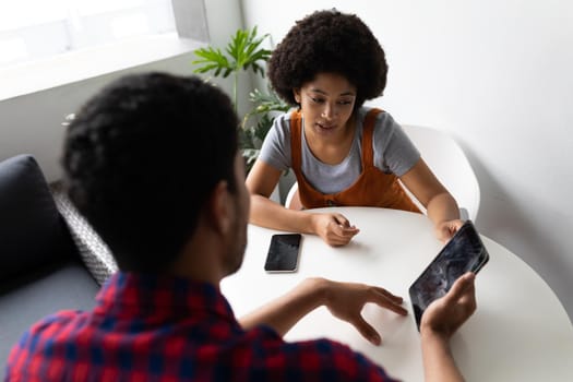 Two mixed race business people working in creative office. two people sitting and discussing work. business people and work colleagues at a busy creative office.