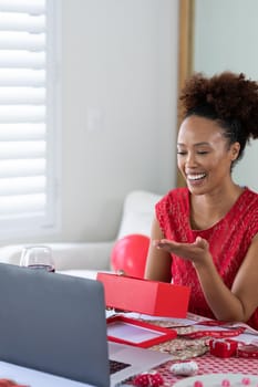 African american woman blowing a kiss on videocall at home. distant celebration of valentines day online and dating concept