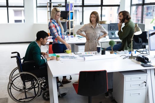 Diverse group of business colleagues looking at blueprints and discussing at table. equal opportunity colleagues working together at a creative office.