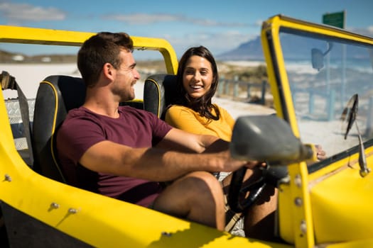 Happy caucasian couple sitting in beach buggy by the sea talking. beach break on summer holiday road trip.
