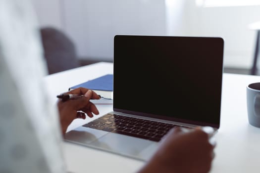 African american woman using laptop with copy space on screen. independent creative business at a modern office.