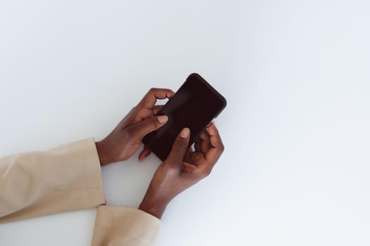 Hand of african american woman holding smartphone with copy space on screen. independent creative business at a modern office.