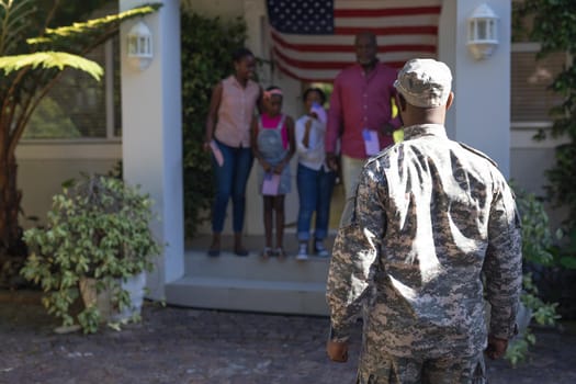 African american soldier father in front of wife, children and father greeting him outside house. soldier returning home to family.