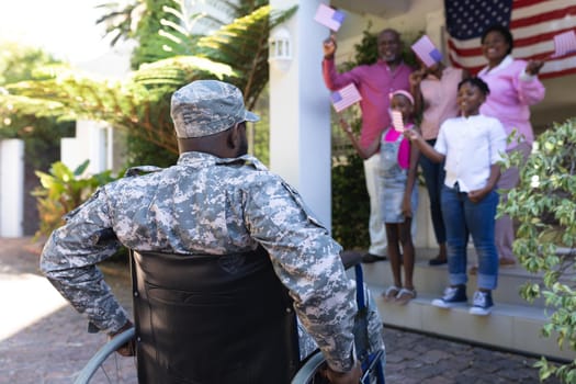 African american soldier father in wheelchair greeting smiling three generation family outside home. soldier returning home to family.