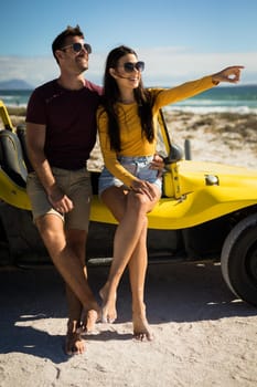 Happy caucasian couple sitting on beach buggy by the sea embracing. beach break on summer holiday road trip.