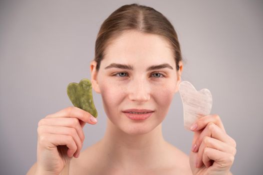 Close-up portrait of a woman holding two gouache scrapers near her face