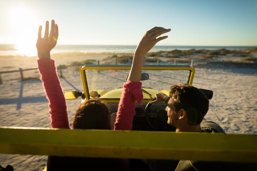 Happy caucasian couple sitting in beach buggy by the sea during sunset. beach break on summer holiday road trip