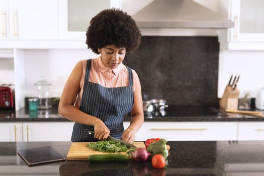 African american woman in kitchen preparing food. staying at home in isolation during quarantine lockdown.