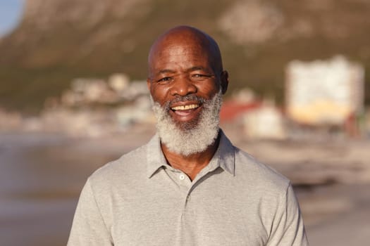 Portrait of senior african american man smiling while standing on the beach. travel vacation retirement lifestyle concept