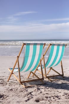 View of two deck chairs on the beach with sea waves. summer beach holiday concept.