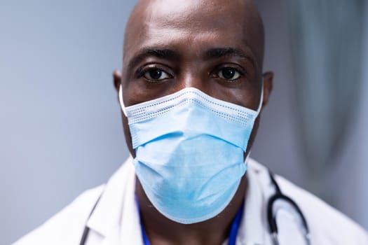 Portrait of african american male doctor in hospital wearing face mask. medical professional at work during coronavirus covid 19 pandemic.