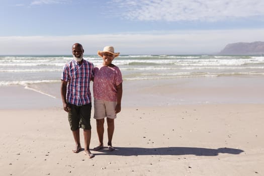 Portrait of happy senior african american couple standing on the beach. travel vacation retirement lifestyle concept