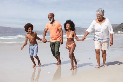 African american grandparents and grandchildren holding hands walking on the beach. travel vacation summer beach concept