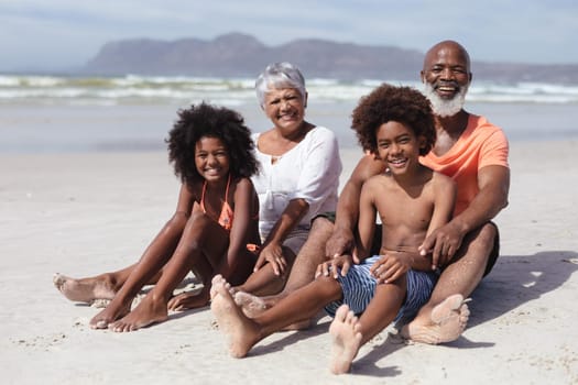 Portrait of african american grandparents and grandchildren smiling while siting on the beach. travel vacation summer beach concept