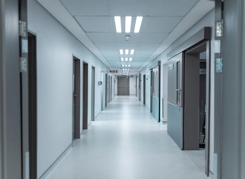 Empty, clean white corridor in modern hospital with overhead lighting, lined with doors. medicine, health and healthcare services.