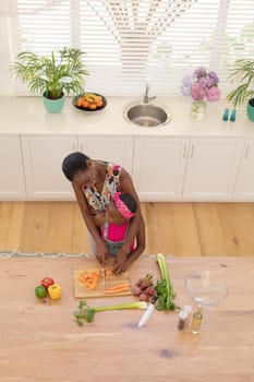 High angle view of african american mother teaching daughter cooking in the kitchen. staying at home in isolation during quarantine lockdown.