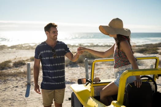 Happy caucasian couple on the beach assistance in getting out of the beach buggy. beach break on summer holiday road trip.