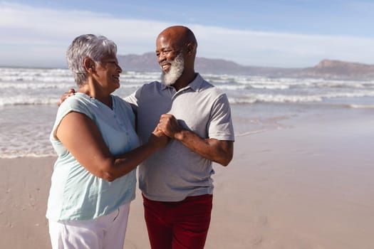 Happy senior african american couple embracing each other on the beach. travel vacation retirement lifestyle concept