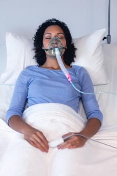 Sleeping african american female patient in hospital bed with oxygen ventilator. medicine, health and healthcare services during coronavirus covid 19 pandemic.