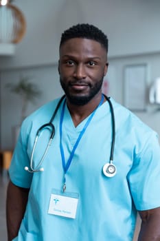 Portrait of african american male doctor with stethoscope wearing scrubs in hospital. medicine, health and healthcare services during covid 19 coronavirus pandemic.