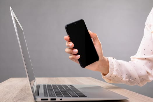 Mid section of businesswoman holding a smartphone against grey background. business, professionalism and technology concept