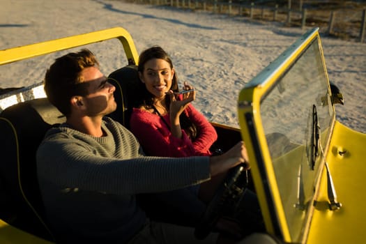 Caucasian couple sitting in beach buggy by the sea during sunset talking by phone. beach break on summer holiday road trip.