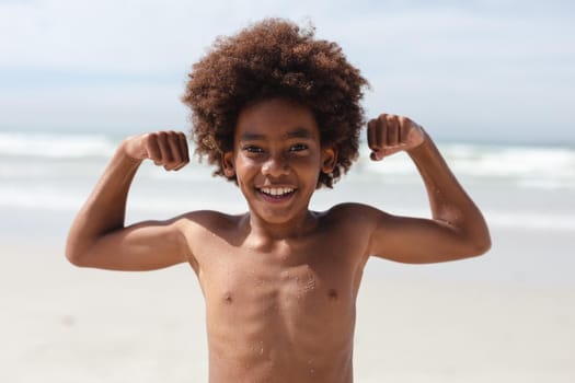 Portrait of african american boy flexing his biceps at the beach. travel vacation summer beach concept
