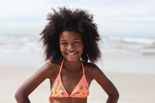 Portrait of african american girl smiling while standing on the beach. travel vacation summer beach concept