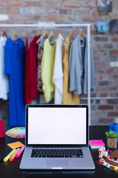 Laptop with copy space on screen lying on desk full of designers accessories. independent creative fashion design business.