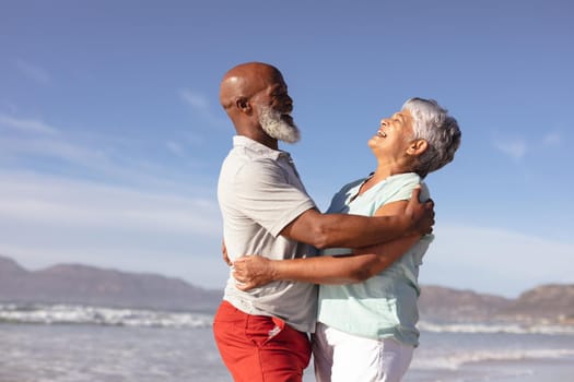 Happy senior african american couple hugging each other on the beach. travel vacation retirement lifestyle concept