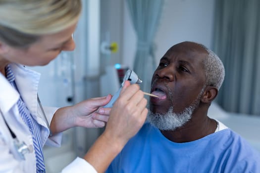Caucasian female doctor examining throat of african american male patient. medicine, health and healthcare services