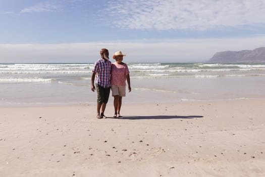 Happy senior african american couple walking together on the beach. travel vacation retirement lifestyle concept