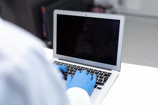 Midsection of doctor wearing latex gloves using laptop with copy space on screen. medicine, health and healthcare services.