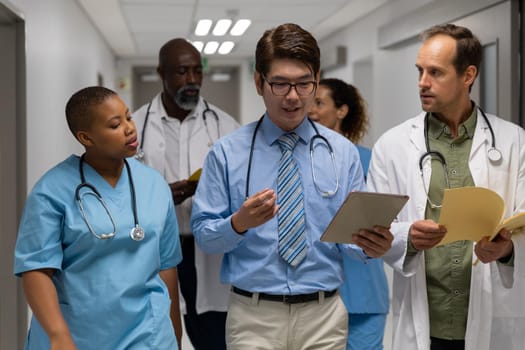 Diverse group of male and female doctors walking through corridor discussing. medicine, health and healthcare services.