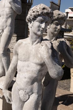 Ancient stone sculptures of naked men in reclamation yard. art and classical style romantic figurative stone sculpture.